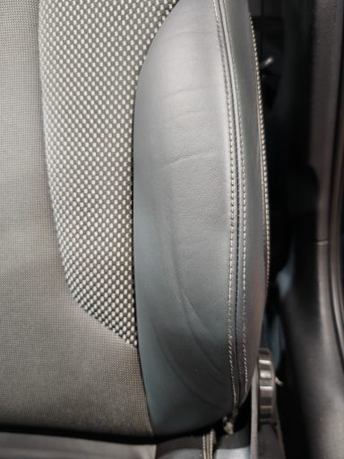 Détail d'un siège de voiture avec revêtement en tissu et cuir.