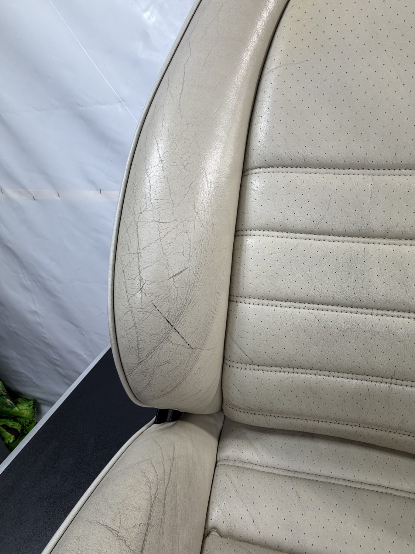 AVANT Détail d'un cuir de siège usé, montrant des craquelures et des marques.