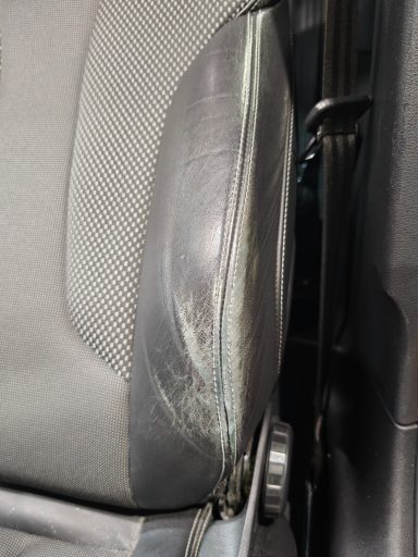 Détail d'un siège avec une usure visible sur le rembourrage et le revêtement.