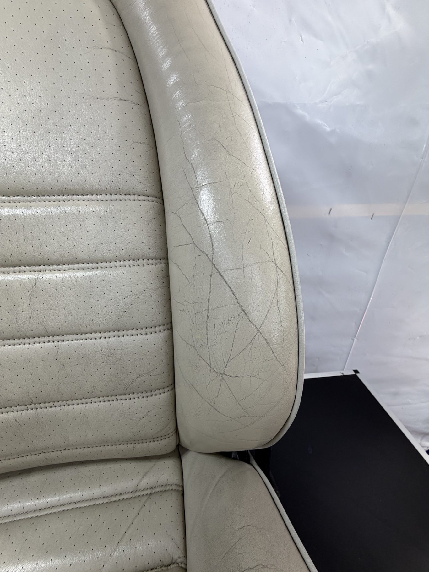 AVANT Détail d'un siège en cuir clair avec des marques d'usure visibles.